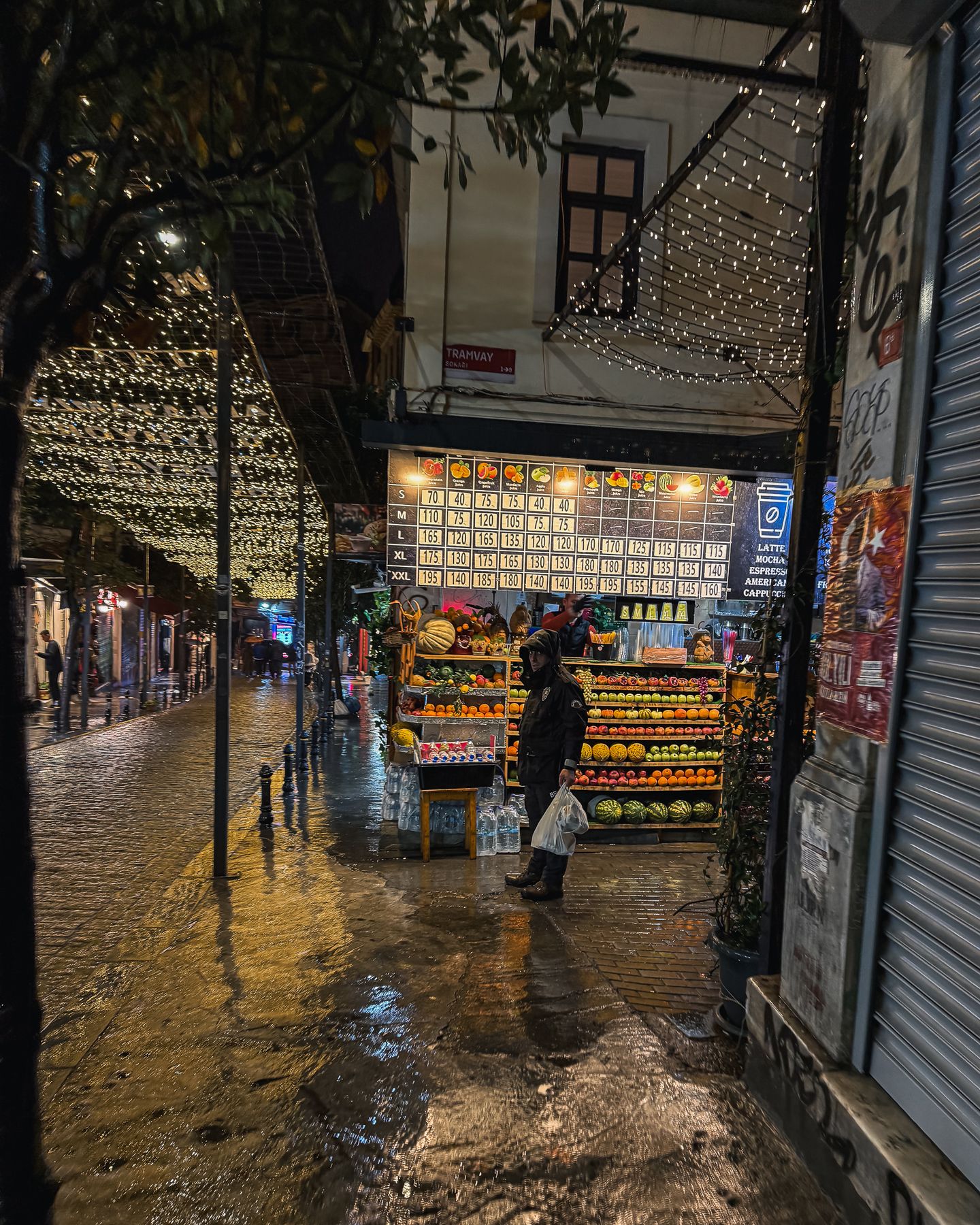 Lit fruit stall on a wet street at night, Istanbul